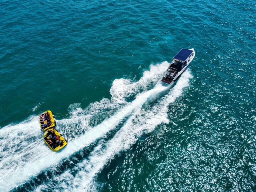 pexels-photo-13315556-13315556 A thrilling aerial view of a motorboat towing inflatable rafts on the ocean, ideal for water adventure enthusiasts.